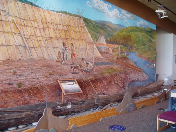 An exhibit showing Nez Perce village life. Also notice the canoe below the mural.
